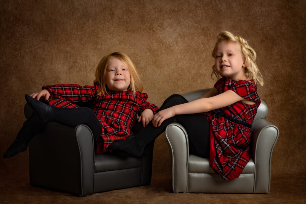 portrait fine-art de 2 sœurs habillées avec robe à carreaux rouge et noir assises dans des fauteuils