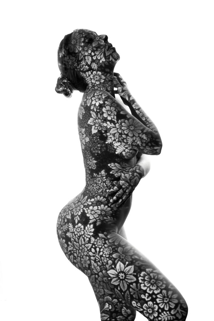 Portrait artistique d'une femme nue recouverte de projections florales, photo en noir et blanc