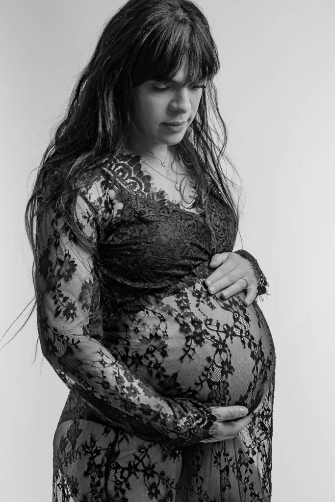 photo studio grossesse femme enceinte vêtue d'une robe en dentelle noire en noir et blanc