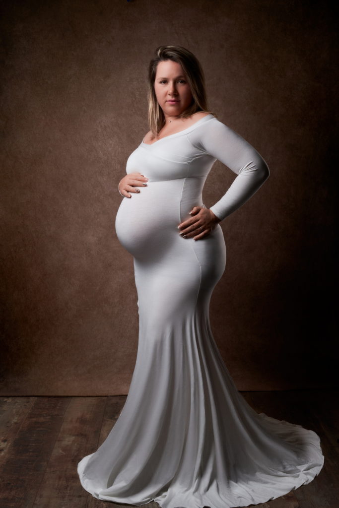 photo studio grossesse femme enceinte vêtue d'une longue robe blanche.