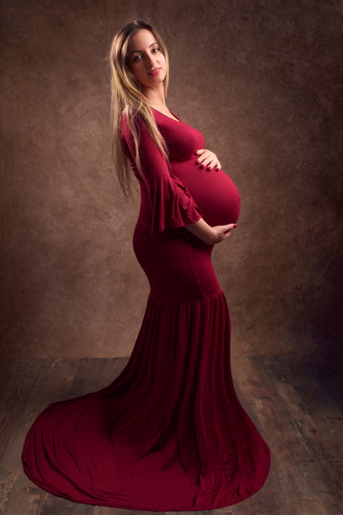 photo studio grossesse femme enceinte vêtue d'une longue robe rouge.
