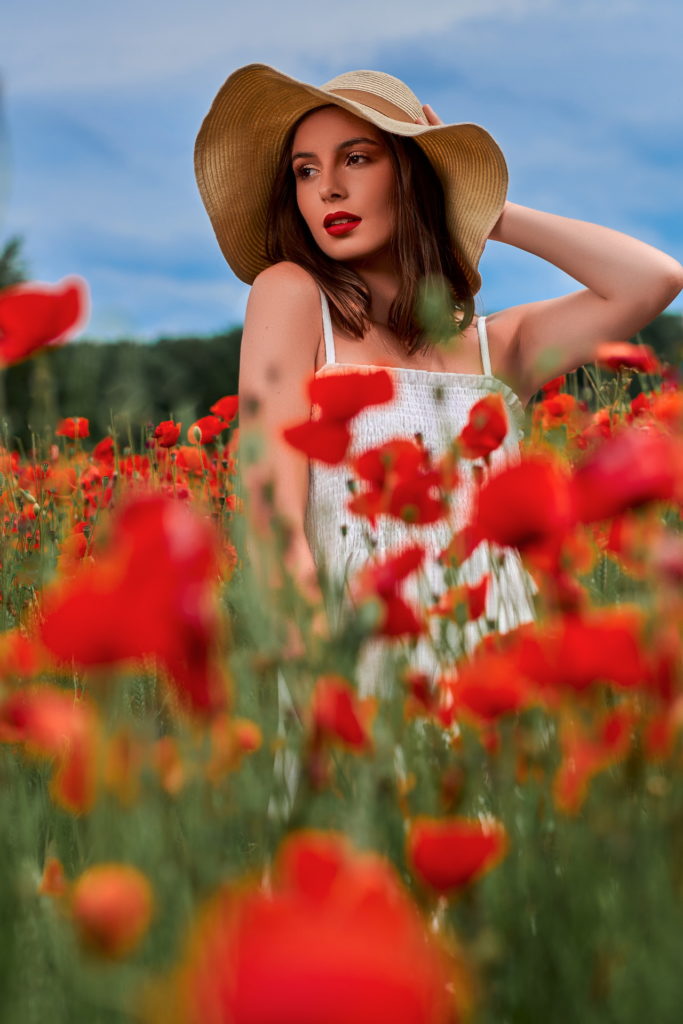 photo d'une femme dans un champ de coquelicot près de Rouen l'été portant une robe blanche et un chapeau de paille